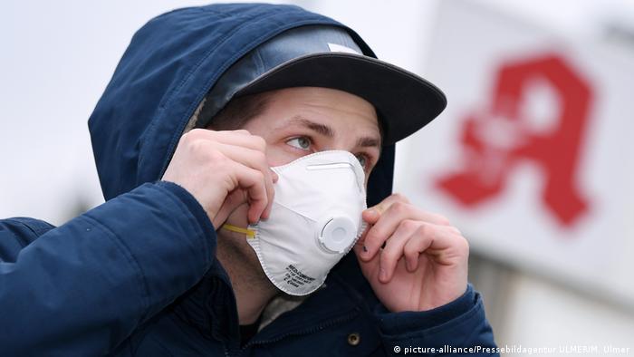 Young man in a protective mask against the background of a pharmacy sign