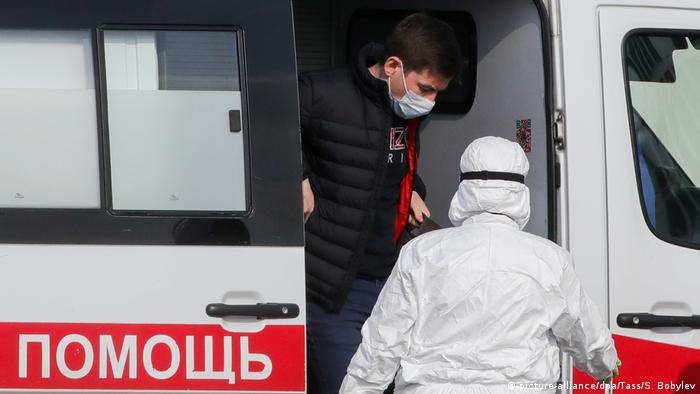 An ambulance with a doctor in a protective suit and patient in a mask